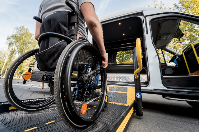 Man rolling wheelchair onto van lift