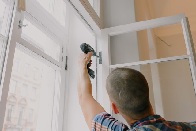 Man using electric drill to install a window