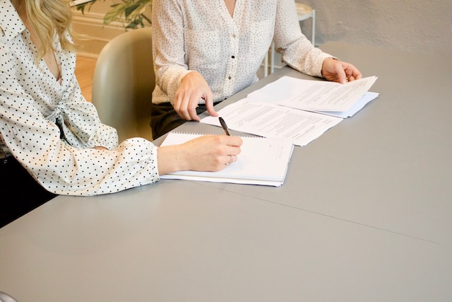 Two women working with papers at a conference table